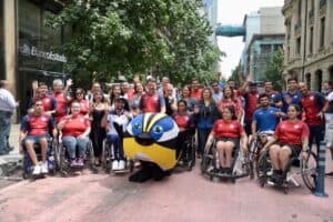 Foto donde aparecec un grupo de deportistas paralímpicos, en su mayoría en silla de ruedas, posando para la foto junto a autoridades y la mascota de los juegos panamericanos.