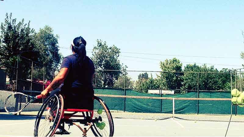 Tenista en silla de ruedas entrenando en una cancha.