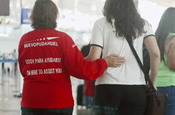 Una trabajadora del aeropuerto está guiando a una pasajera con discapacidad visual en el aeropuerto de Santiago