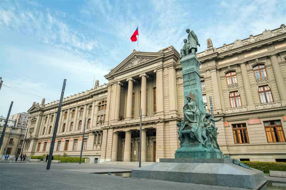 foto de la fachada del edificio de la Corte Suprema de Chile y se alcanza a apreciar un parte del cielo celeste. Hay un cuadro blanco que dice: Corte Suprema declara que síndrome de Down no es una enfermedad y ordena dar cobertura de salud.