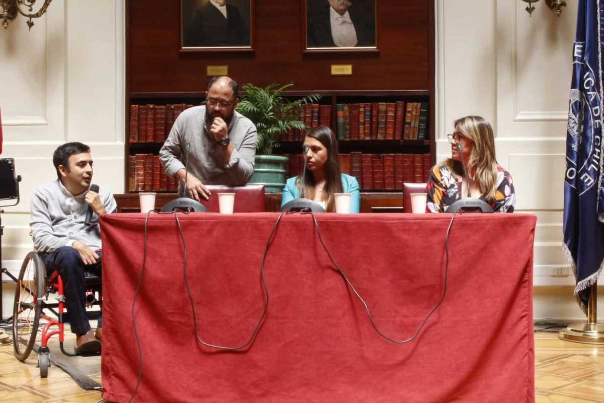 Foto donde aparecen 4 personas sentadas en una mesa frente al público conversando.