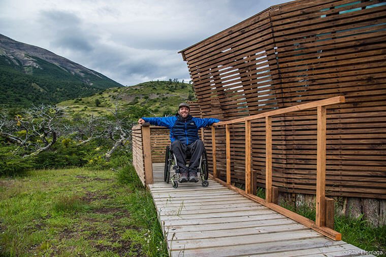 Foto de una persona en silla de rudas sobre un sendero accesible en un parque nacional.
