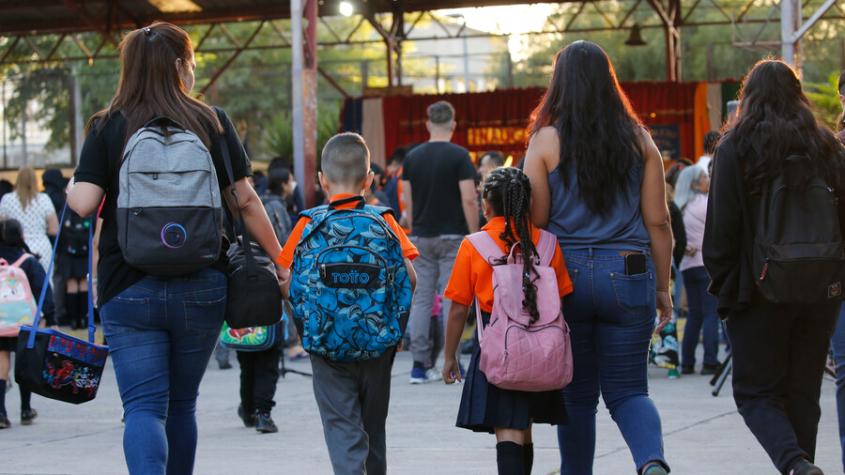 Foto de dos madres y sus dos hijos caminando hacia el ingreso de un colegio.
