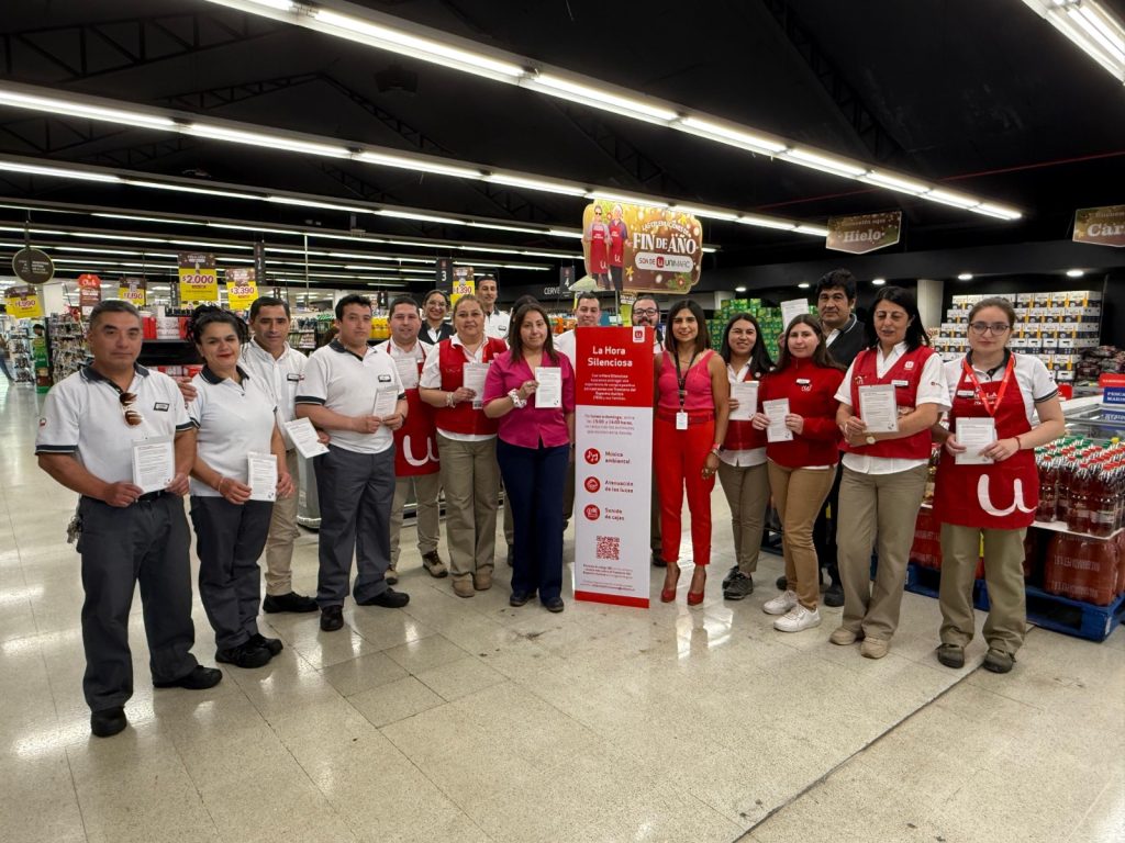 Foto dentro de un supermercado unimarc donde aparecen algunos trabajadores mostrando un cartel que dice hora silenciosa.