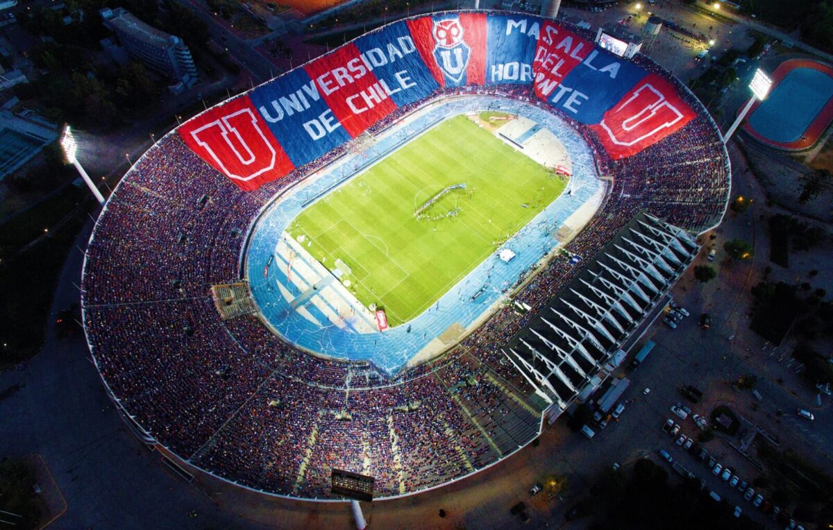 Foto del estadio nacional sacada desde el cielo. Se ve el estadio lleno y la cancha de pasto verde.