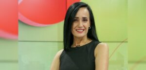 Foto de perfil de la periodista carolina gutierrez quien aparece en un estudio de televisión y sonriendo a la cámara.