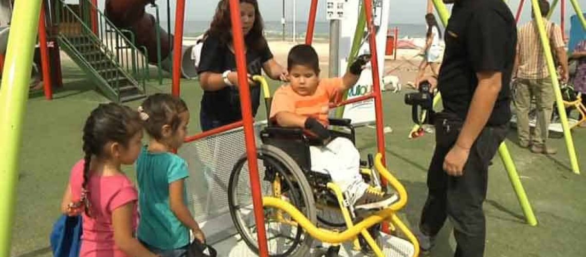 Niño columpiándose en una plaza accesible.