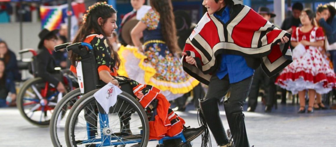 Foto de una niña en silla de ruedas bailando cueca junto a un compañero de baile en su escuela.