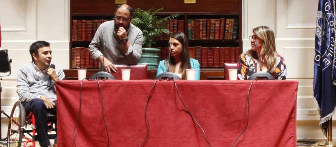 Foto donde aparecen 4 personas sentadas en una mesa frente al público conversando.