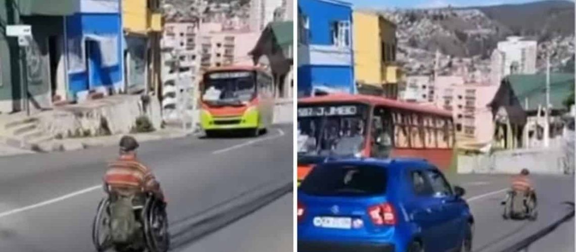 Pantallazo de un video donde aparece una persona en silla de ruedas bajando por una calle en un cerro de valparaíso, y de frente hay una micro y atrás de él viene un auto que lo intenta adelantar.