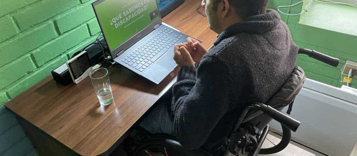 Hombre en silla de ruedas frente a un computador