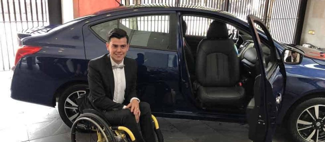 Un joven en silla de rudas posa para la foto al lado del nuevo auto adaptado