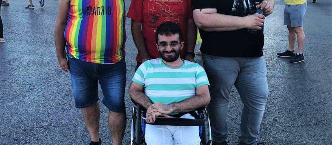 Foto donde aparecen 4 personas posando para la foto durante una marcha del Orgullo LGBTI en España. Están abrazados y uno de ellos está en silla de ruedas.