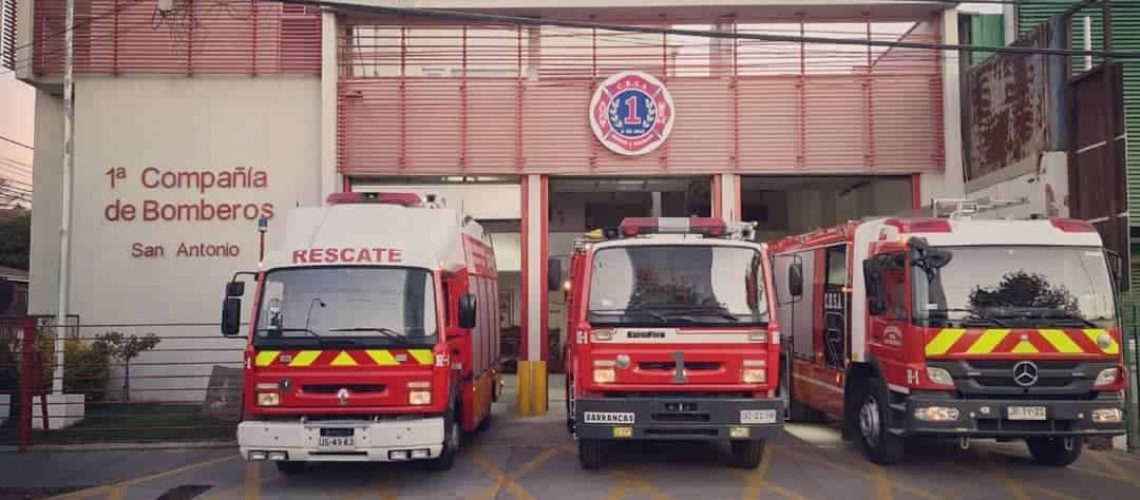 Foto de la 1era compañía de bomberos de san antonio donde hay 3 carros de bomberos grandes estacionados en la entrada.