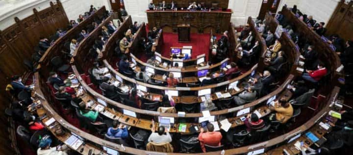 Foto del pleno de la convención constituyente donde aparecen varias personas votando en sus asientos.