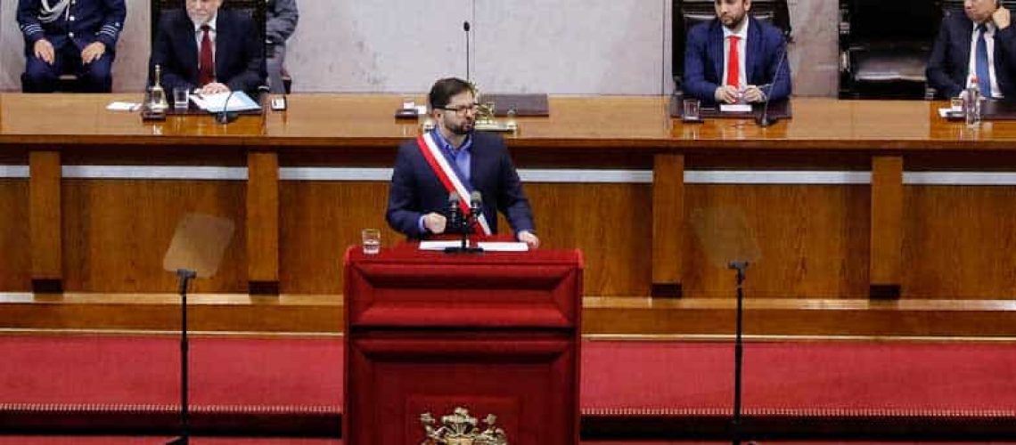 Foto dentro del congreso nacional donde aparece el presidente gabriel boric hablando sobre un estrado vestido de terno y con la banda presidencial.