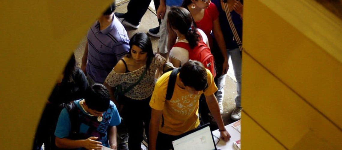 Foto de un grupo de jóvenes haciendo una fila para realizar una postulación en una universidad