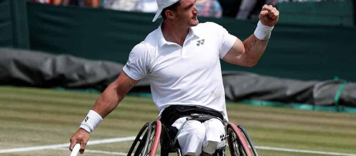 El tenista argentino Gustavo Fernández en su silla de ruedas celebrando un punto en un partido de tenis sobre una cancha de pasto.