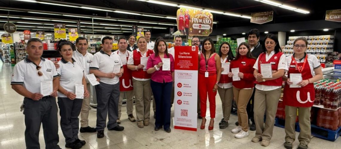 Foto dentro de un supermercado unimarc donde aparecen algunos trabajadores mostrando un cartel que dice hora silenciosa.