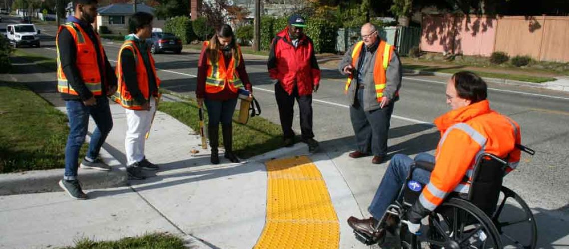 Aparece un grupo de ingenieros en la esquina de una calle en Seattle Estados Unidos, y uno de ellos está en una silla de ruedas intentando subir a la vereda.