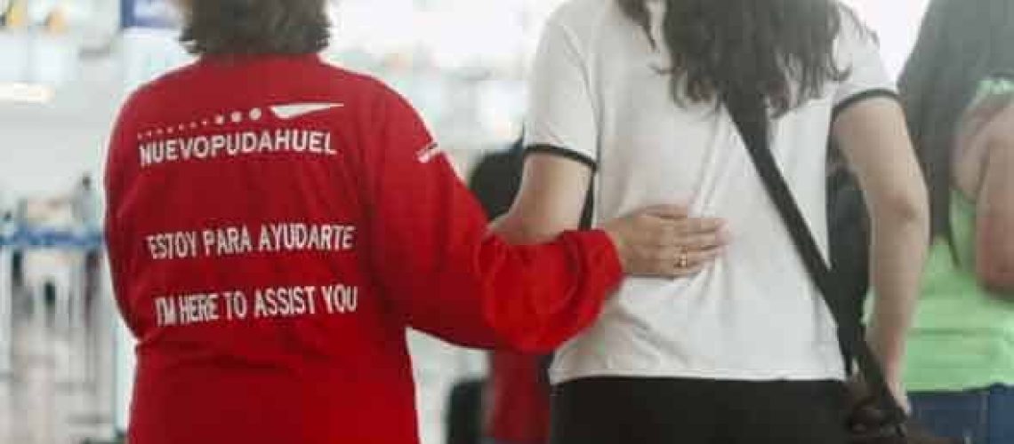 Una trabajadora del aeropuerto está guiando a una pasajera con discapacidad visual en el aeropuerto de Santiago