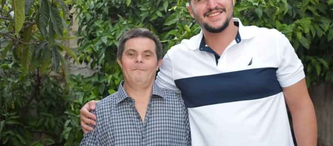 foto donde aparece un joven abrazado a su padre que tiene síndrome de Down. Ambos sonríen y miran a la cámara.