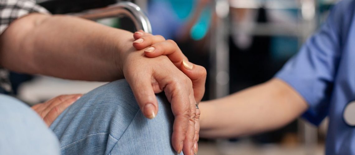 Foto de una persona en silla de rueda recibiendo una mano de otra persona