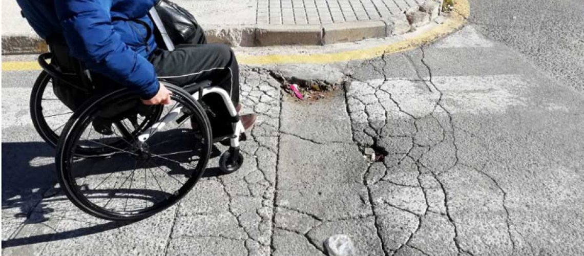 Foto de una mujer en silla de ruedas cruzando una calle en santiago.