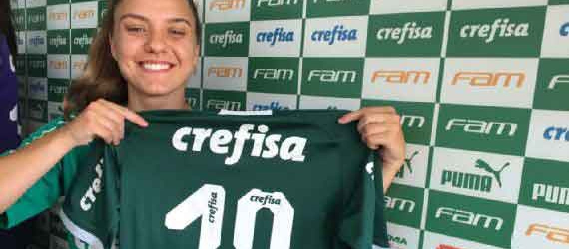 Una futbolista sorda sonriendo a la cámara y mostrando la camiseta que usará en su nuevo club