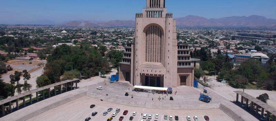 Foto desde el cielo donde aparece el templo votivo de maipú que contiene una gran explanada y al final hay una iglesia muy alta. De fondo se ve la comuna de maipú.