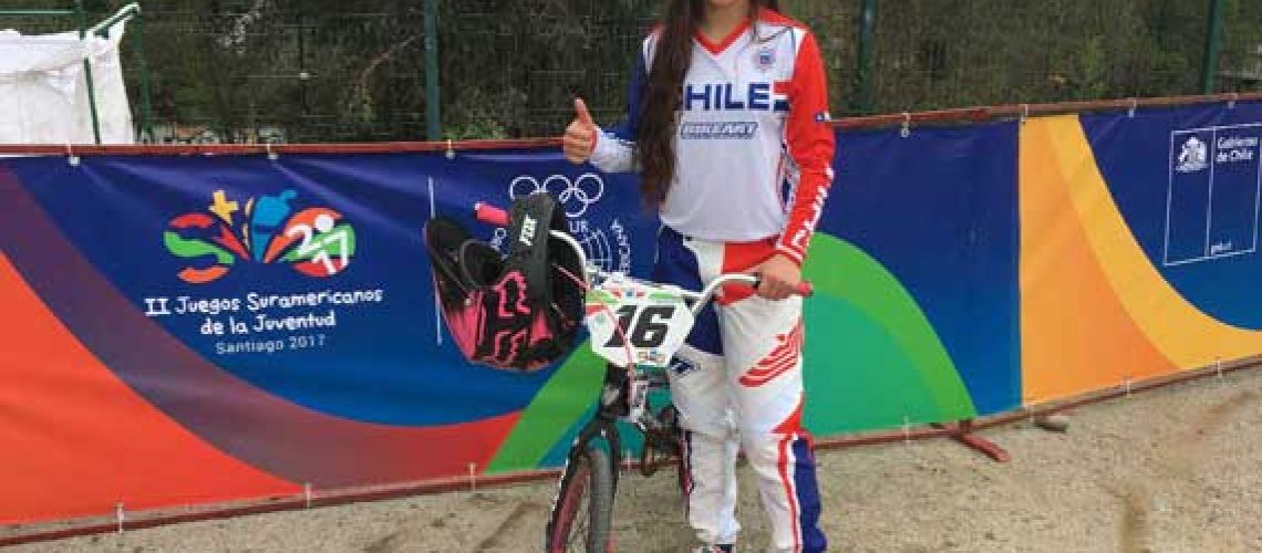Una joven sonriendo junto a su bicicleta previo a una carrera de BMX