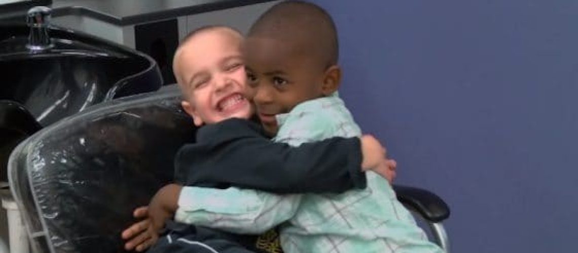 Dos niños de diferentes razas se abrazan con cariño y ríen.