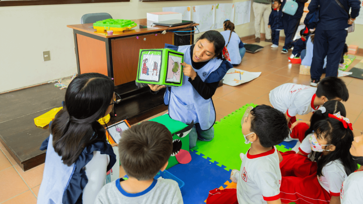 Foto dentro de una sala de clases en una escuela especial donde la profesora le muestra pictogramas a sus alumnos.